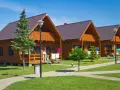 Gotowy domek letniskowy całoroczny, z drewnianą elewacją i balkonem, stoi na zielonym trawniku.
