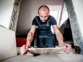 Remont trwa, a mężczyzna w ogrodniczkach zastanawia się, gdzie wyrzucić stare płytki ceramiczne.