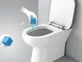 Ręce w rękawiczkach umieszczają kostkę czyszczącą w toalecie. Idealne wc na działkę projekt.