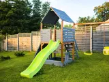 Drewniany domek ze zjeżdżalnią i huśtawkami. Idealne miejsce do zabawy, jak zrobić schody do domku dla dzieci?