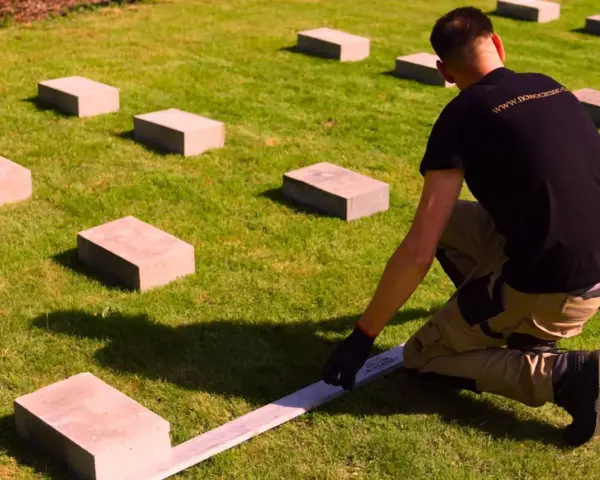 Ustawianie bloczków betonowych na trawniku to pierwszy krok, jak zrobić podłoże pod domek ogrodowy. Precyzyjne rozmieszczenie to klucz do stabilnej konstrukcji.