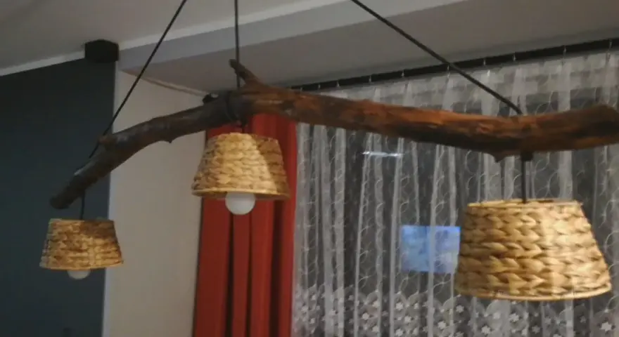 Jak odnowić stary drewniany żyrandol? Ta rustykalna lampa z gałęzi i plecionych kloszy z pewnością doda uroku wnętrzu.