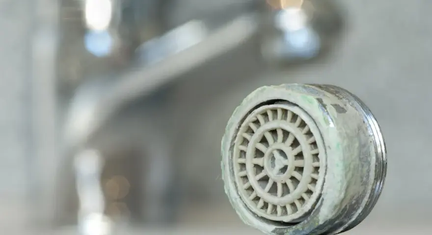 Zwapniony aerator kranu, który pokazuje, jak wyjąć sitko z kranu.