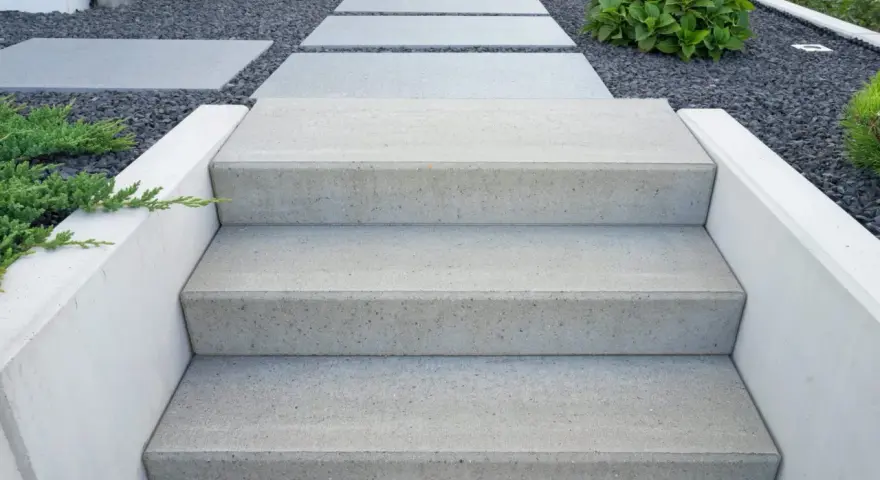 Nowe schody do ogrodu zrób sam. Nowoczesne, betonowe stopnie prowadzą przez kamienny żwirek do zieleni.