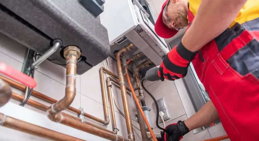 Instalator pracuje przy kotle gazowym, przygotowując go do zmiany właściciela. Dowiedz się, jak przepisać gaz na nowego właściciela PGNiG.